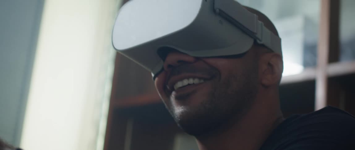 A man is smiling and playing a virtual reality game