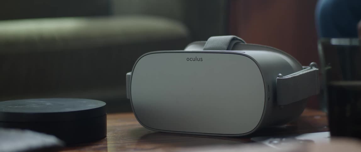 A man sets an oculus virtual reality headset and controller on a table and walks away