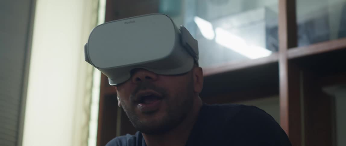 A man plays a virtual reality game while sitting indoors during the day