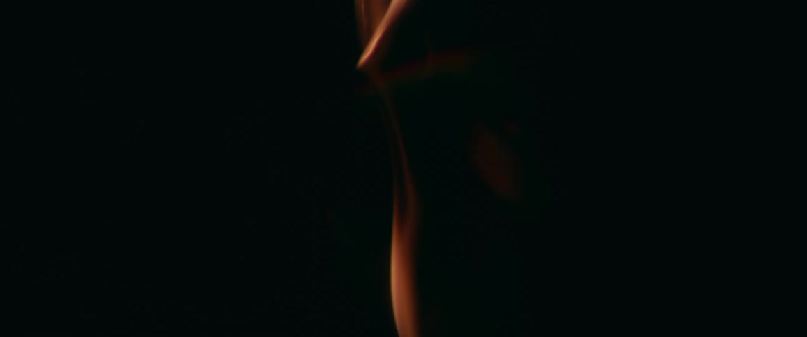 Close up of dim orange flames rising up against a black background