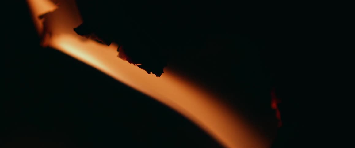 A flame is moving under a rough object and waving in the darkness