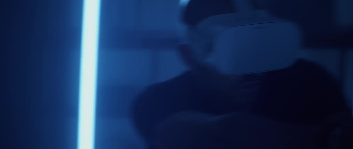 A man wearing a virtual reality headset looks around apprehensively while playing a game