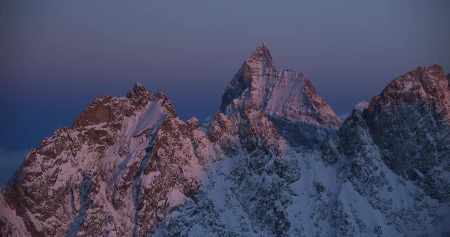 An aerial view of a snowy mountain range in the wilderness at sunrise