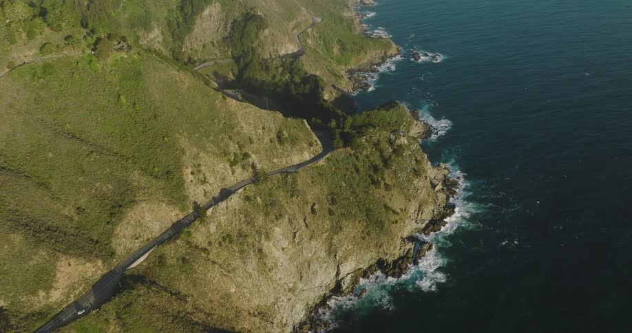 A road along the sheer coast of a landmass during the day