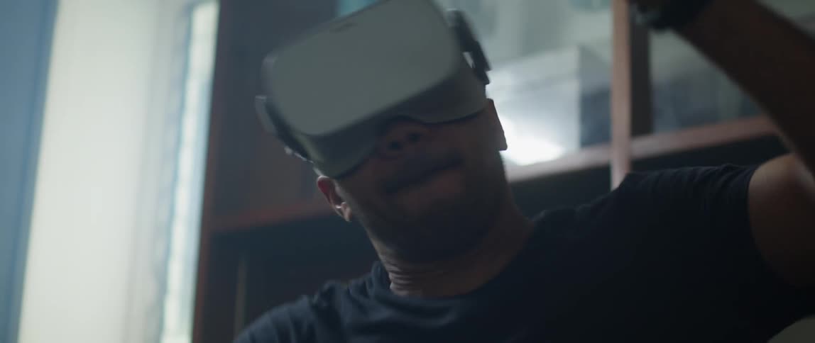 A man smiling and swinging his arm around while wearing a virtual reality headset