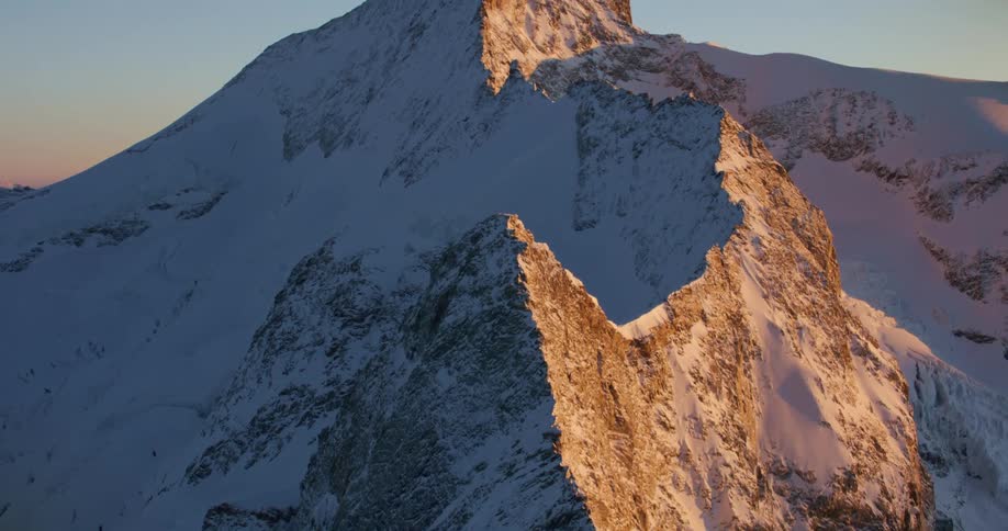 Sun highlights rock faces of snow covered mountain