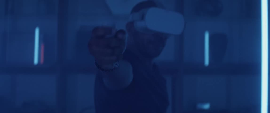 Man wearing black t shirt and equipped with virtual reality headset plays shooting game with controller