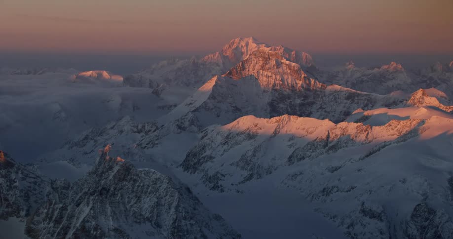 A snow covered mountain range as the sun sets