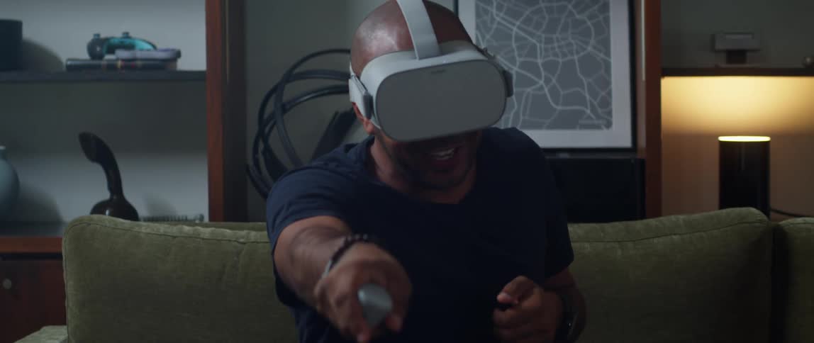 Man wearing virtual reality headset smiles after gesturing during gaming