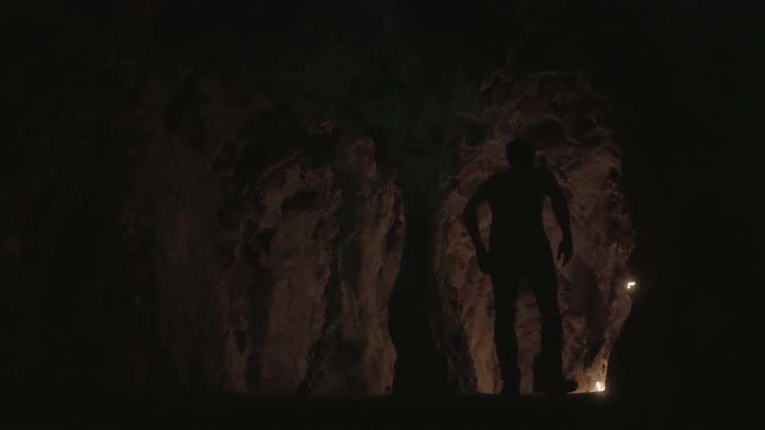 A hunched over man in a cave