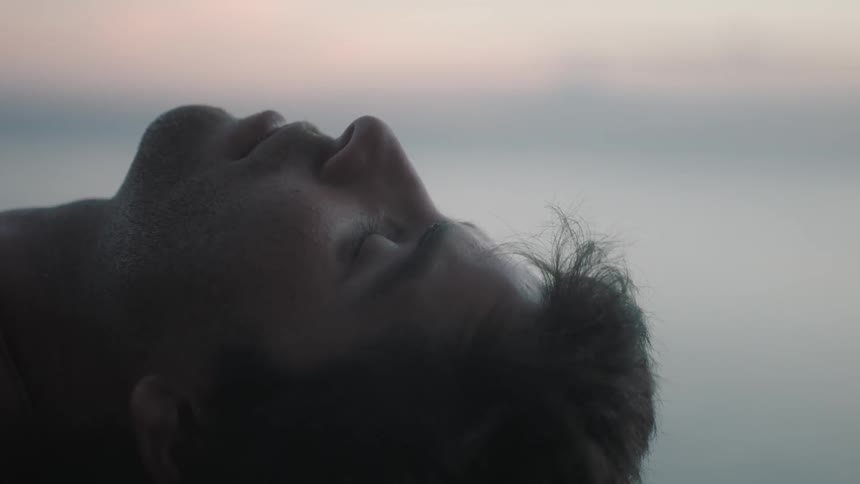 A man lying in somewhere at dusk opens his eyes