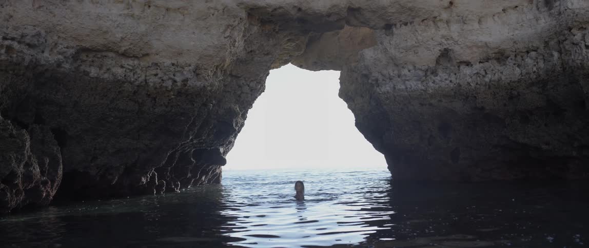 Person treading water in a cavernous area of the beach