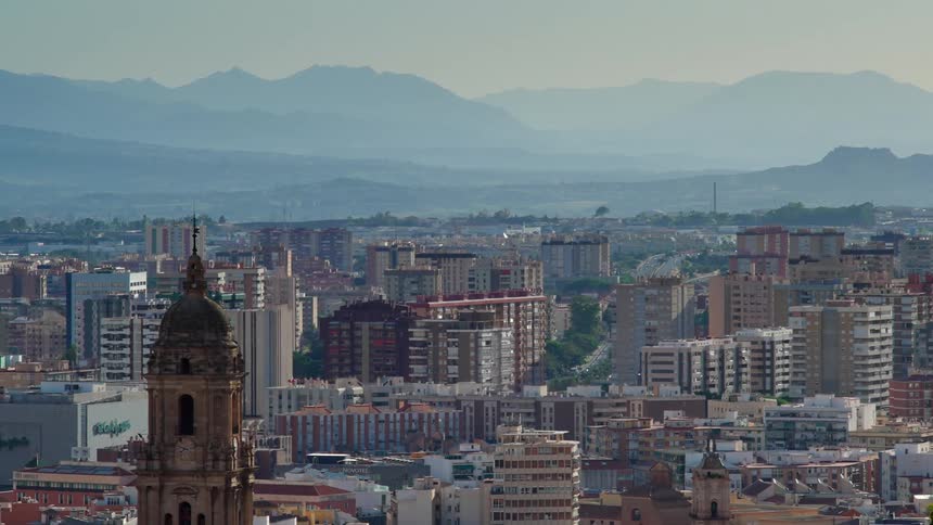 Town stretches between church with tower and foggy mountains on horizon