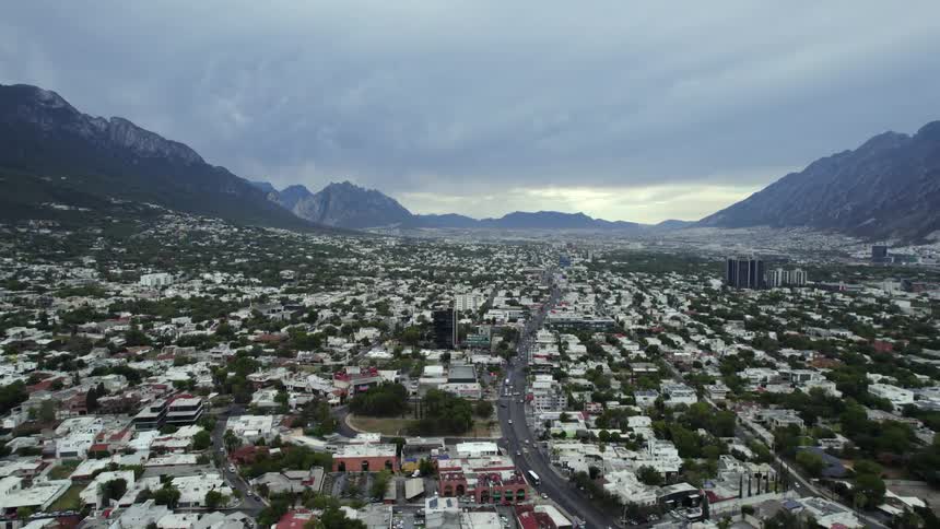 Traffic flows down highway through center of town in misty valley surrounded by mountains