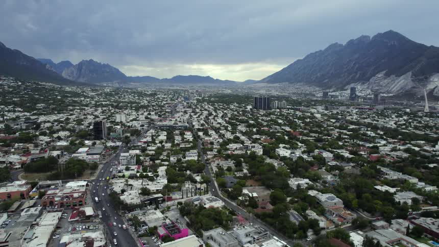 Vehicles drive through a dense suburb near mountains