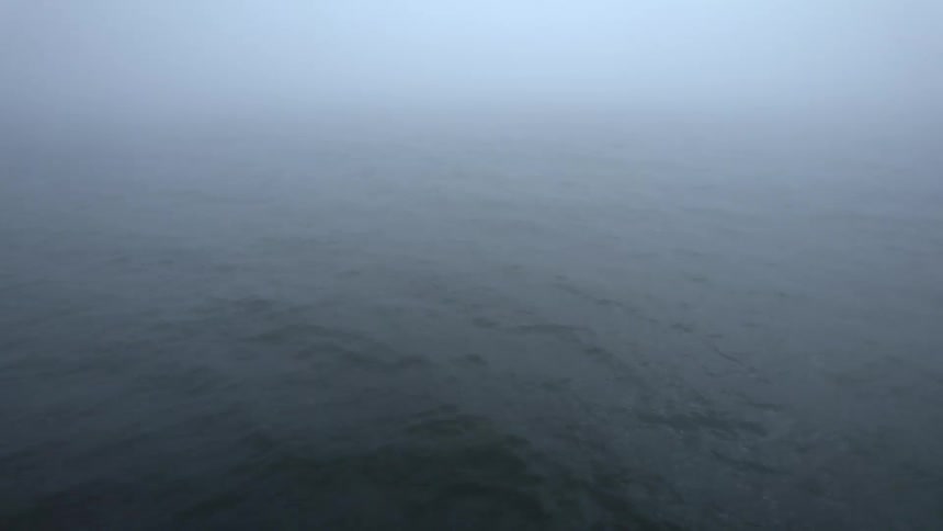 Aerial view of the gentle ocean waves under a thing layer of mist