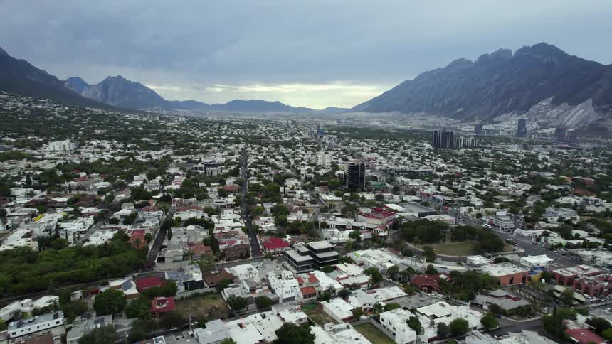 Small city stretches between mountains under an overcast sky on a foggy day