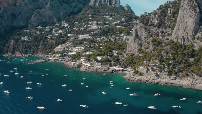 An aerial view of mountains on the coast with boats in the water