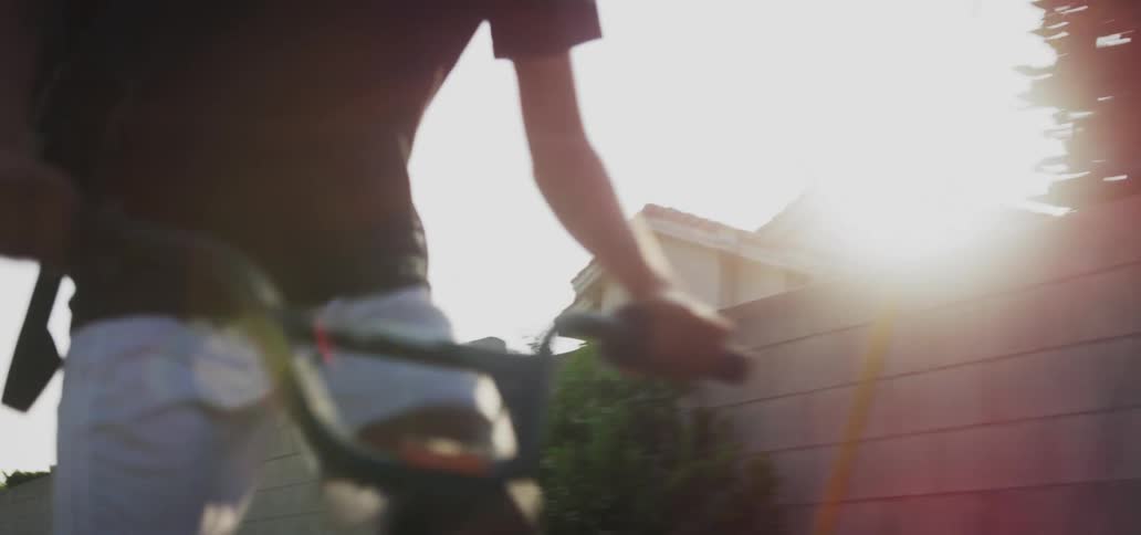 Teenage boy with a backpack riding a bicycle in a residential neighborhood
