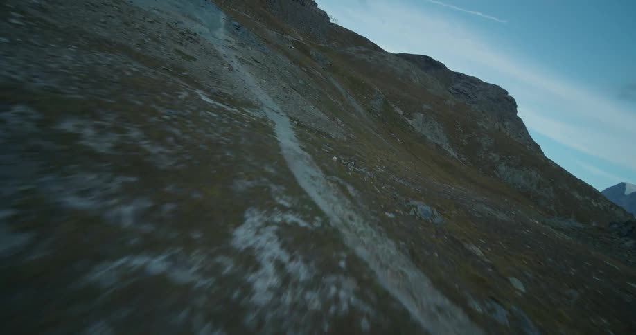 A rock pile cairn along a winding trail on a mountain slope
