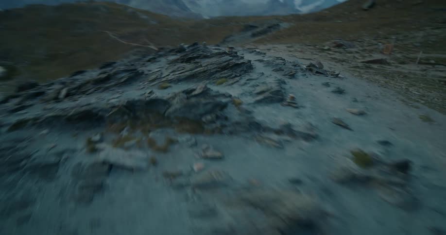 Aerial twisting flyby close to the surface over the rugged rock slopes of a mountain at daytime