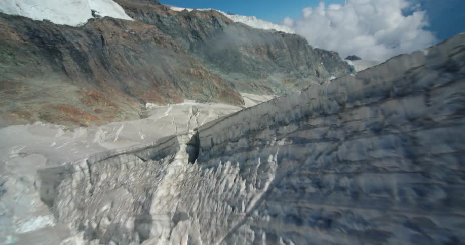Aerial flyby over the rugged ice surfaces of a glacier on the slopes of a mountain at daytime