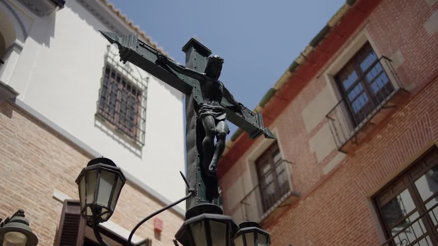 A religious statue is near some street lights in a neighborhood