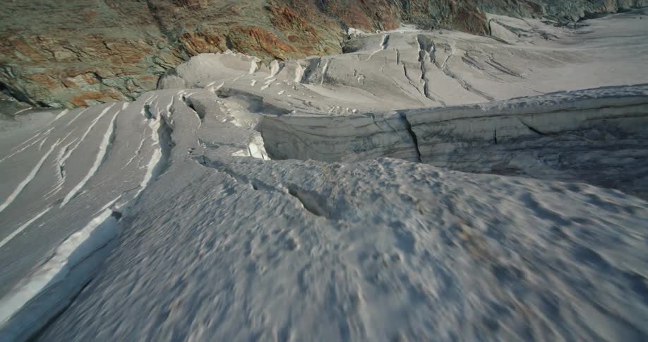 Aerial flyby over the rugged ice surface of a glacier in the mountains at daytime