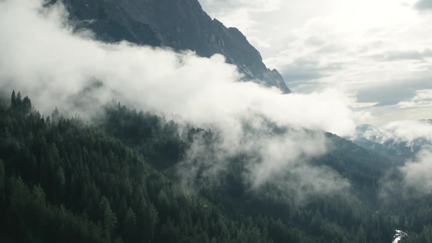 Aerial view of a thick layer of white clouds covering the slopes of a mountain range at morning