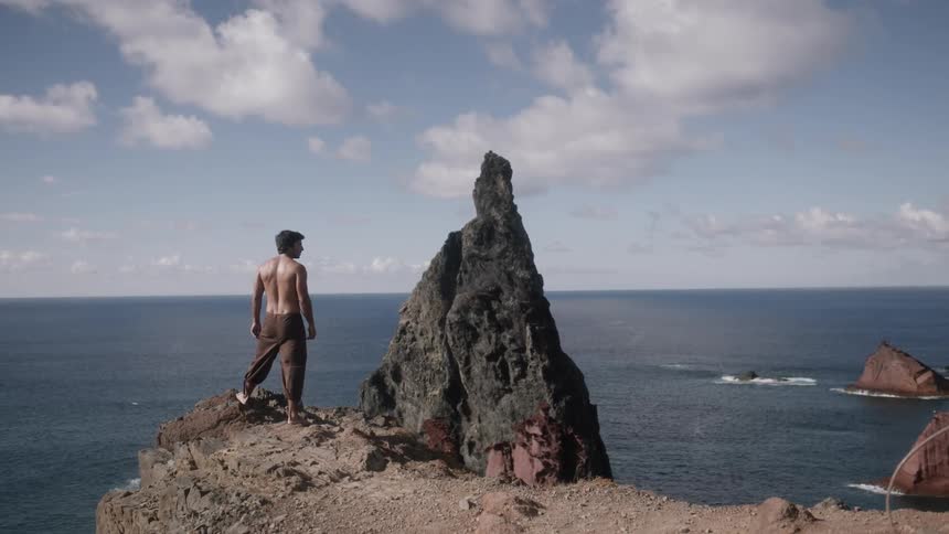 Man standing atop a rocky area overlooking the sea