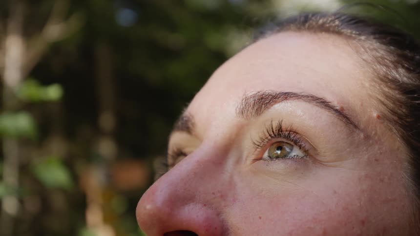 Woman stands outdoors looking upward