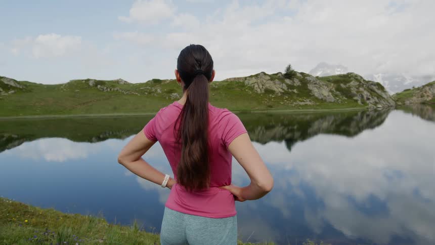 A woman stands and looks out across a lake