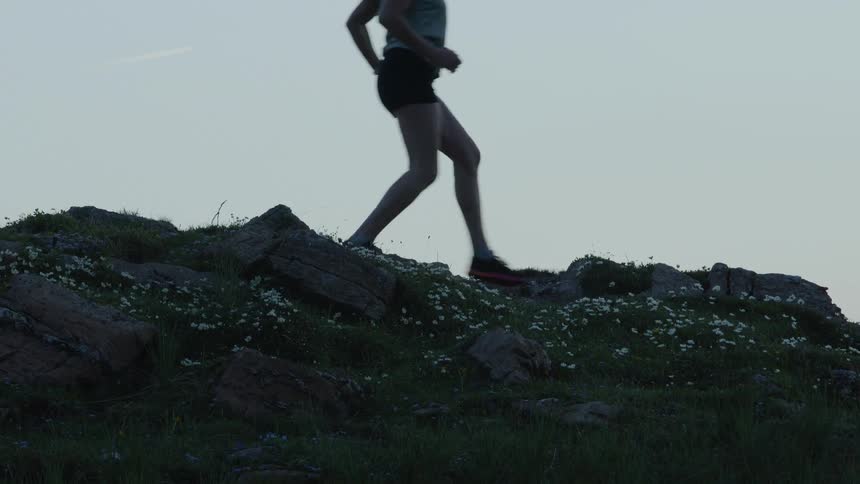 A woman runs across rocky ground