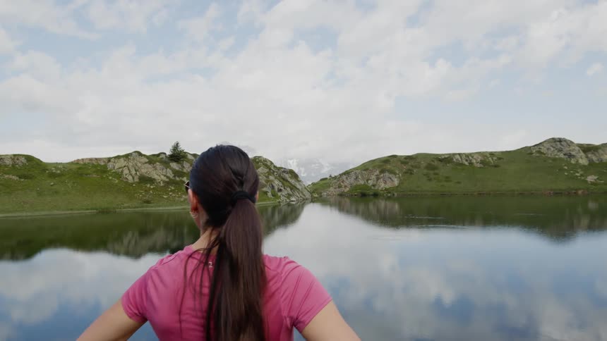 A woman stands and looks out at a lake