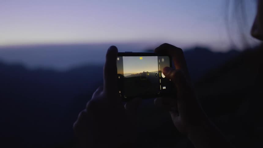 Woman uses smartphone to take pictures of the landscape at night