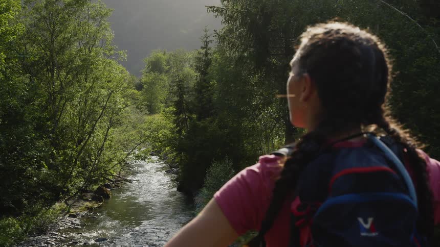 A teenager stands over a creek in the woods