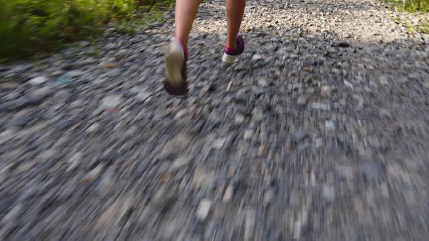 Female jogger runs across gravel path