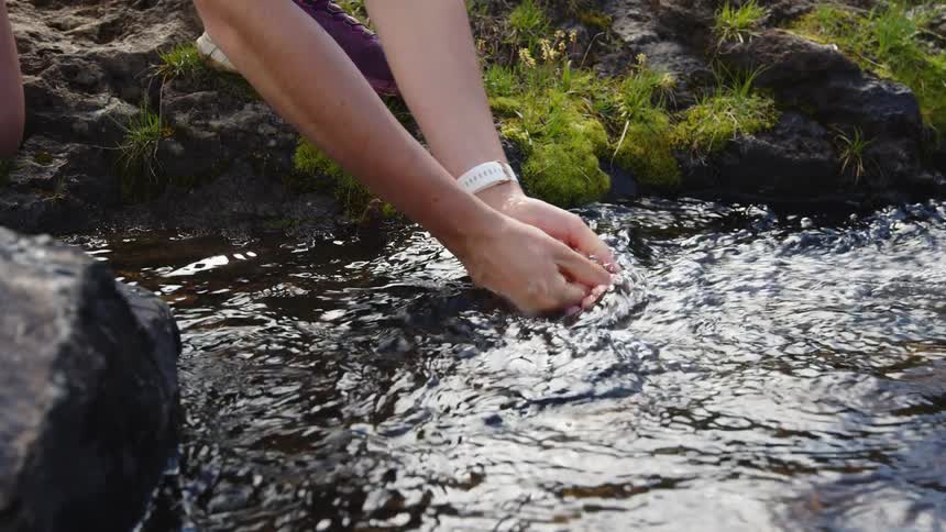 Person is washing their hands in a stream of water