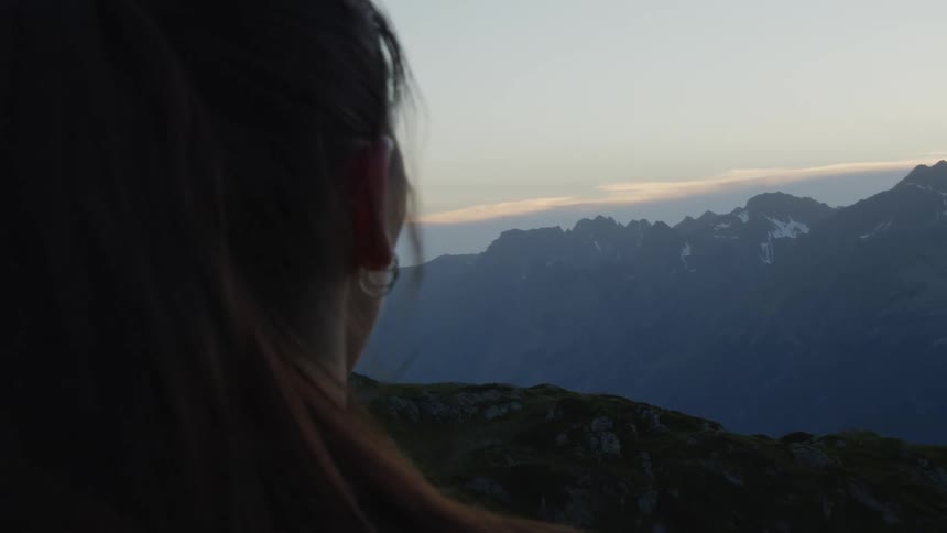 A woman is standing outdoors and looking at the mountains