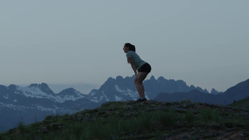 A young white person is jogging in the forest and looking at some mountains