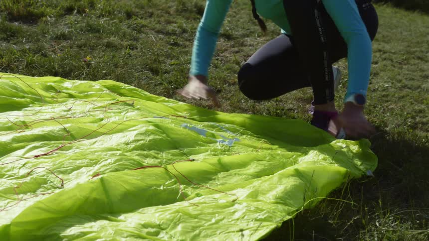 A woman is outdoors and is setting up a a paragliding canopy
