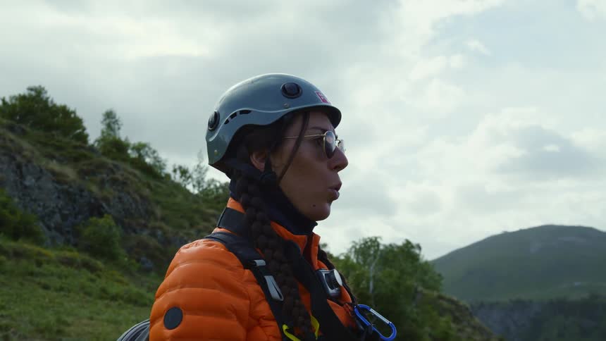 A woman is outdoors and is wearing a helmet before going paragliding