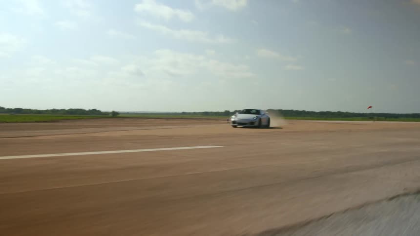 A car speeds along a runway outdoors on a clear day