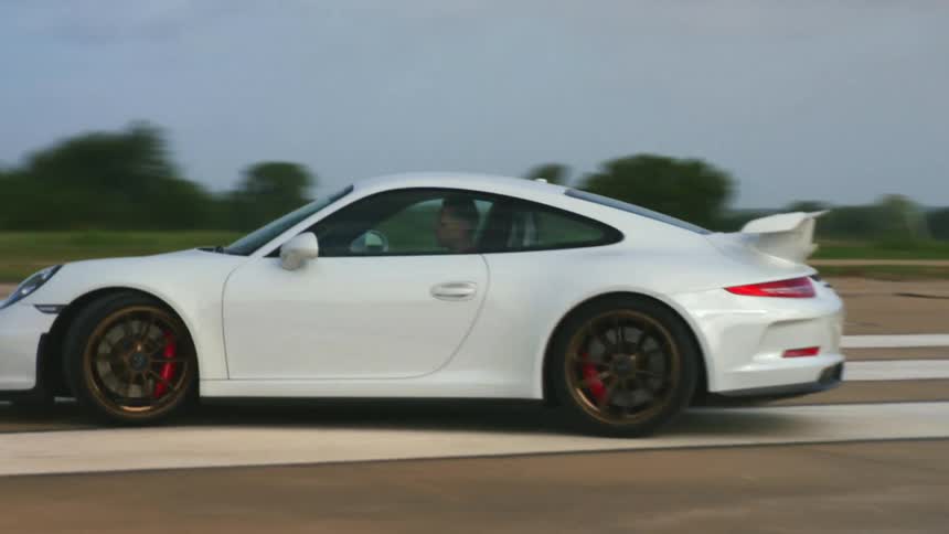 A man drives around in a white porsche vehicle at daytime