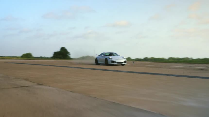 A porsche travels on an empty secluded strip