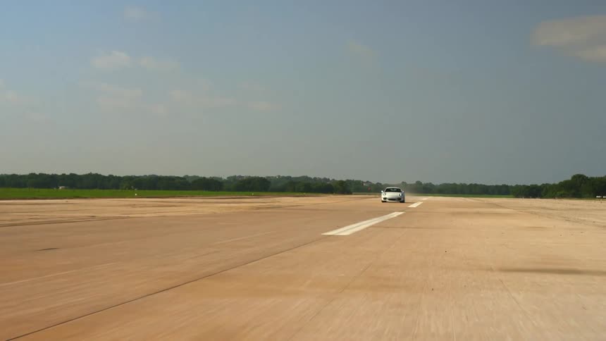 A vehicle is driving down a grasslined road
