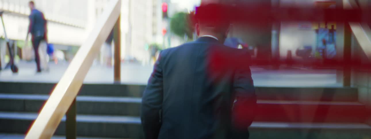 A man is walking on the stairs to exit a building in a city
