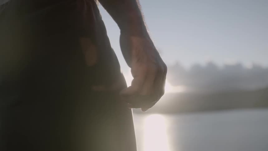 A man standing next to a body of water at sunset