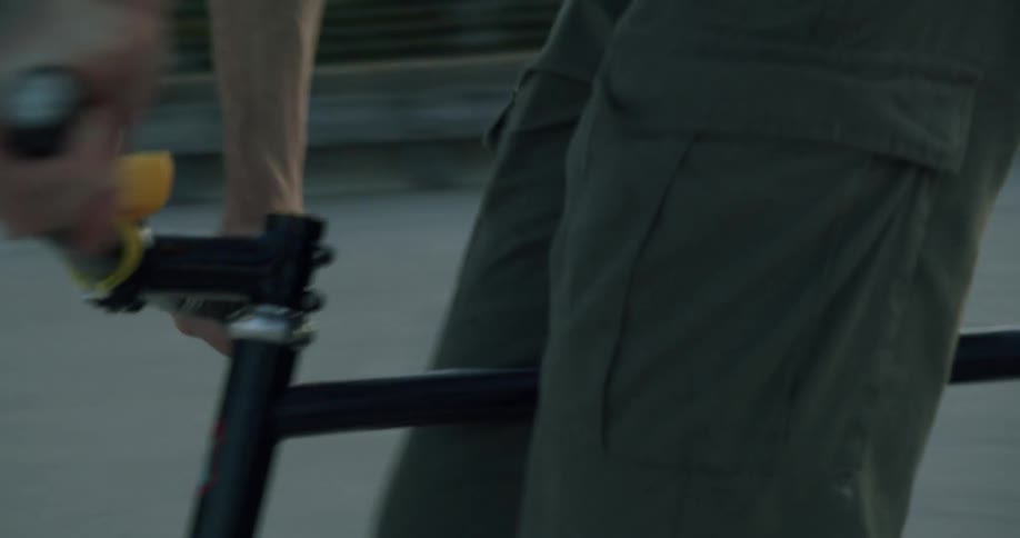 Close up of a man riding a bicycle on the roof of a parking garage at evening