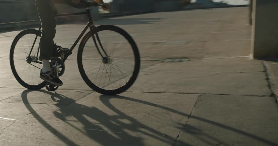 A man jumps on a bicycle and rides it into a parking structure